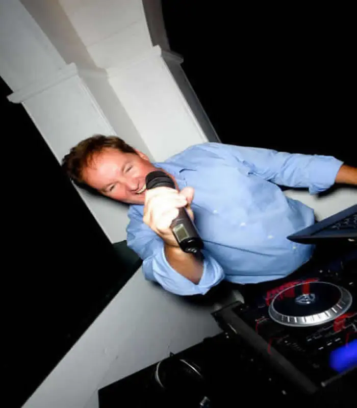 Chris James leaning over the decks with a microphone
