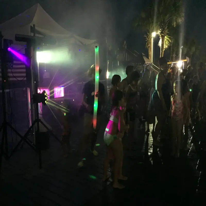 Crowd dancing with glow sticks at a Chris James glow party