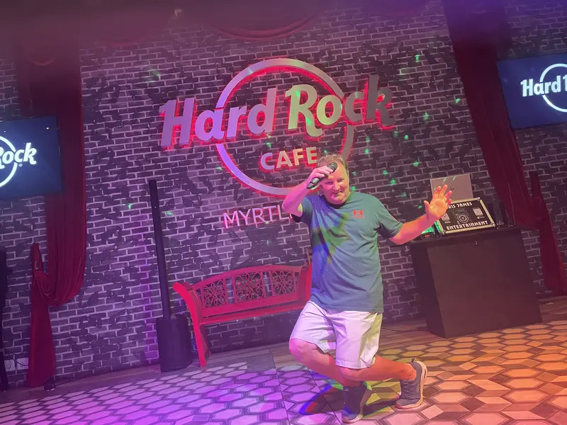 DJ Chris James dancing in front of the Hard Rock Cafe sign in Myrtle Beach