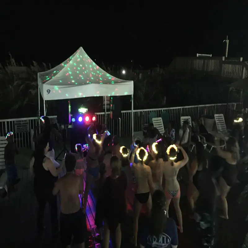 Guests dancing under a lit tent at a night party with DJ Chris James