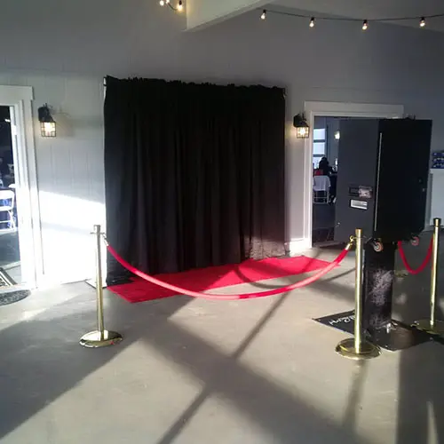 Open photo booth with a black backdrop and red carpet